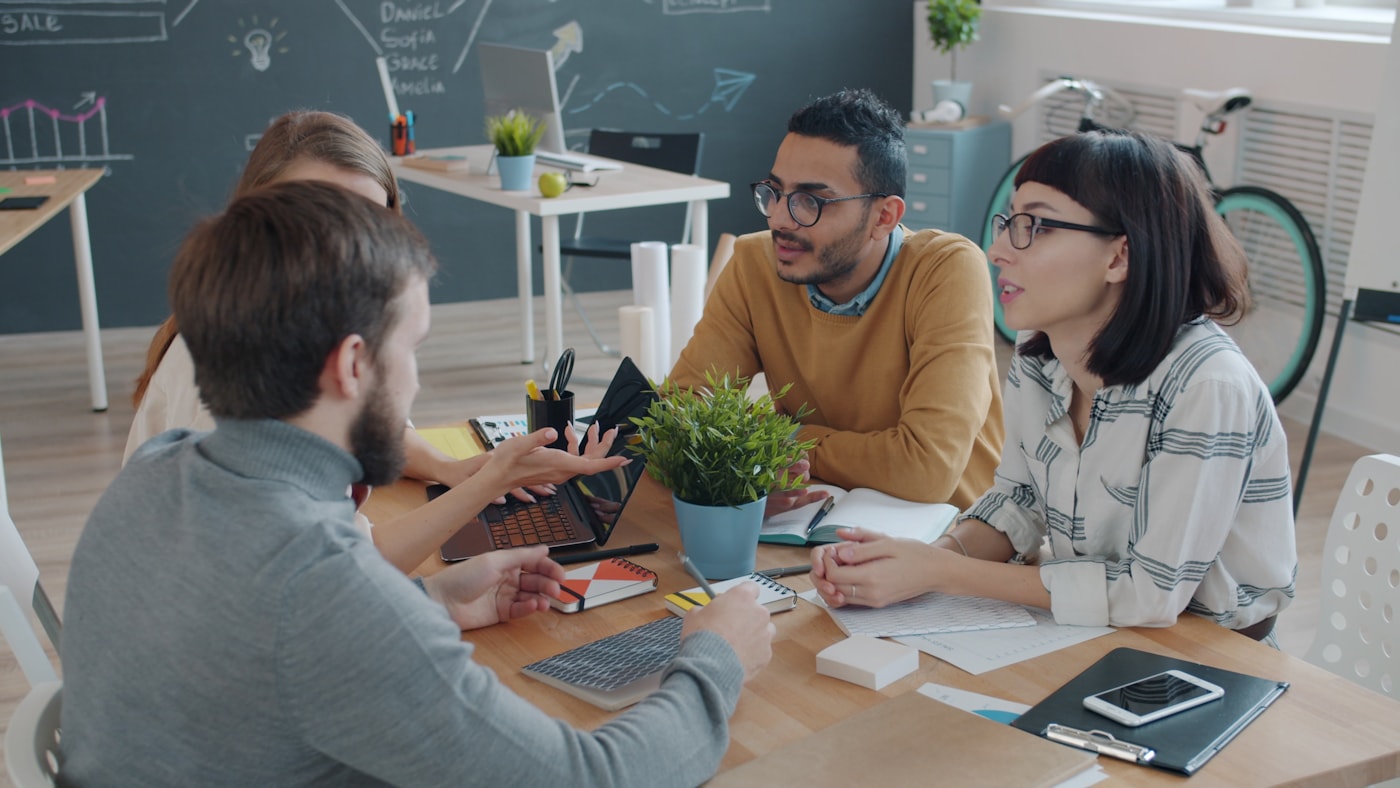 Equipe diversa conversando em uma reunião colaborativa em escritório criativo