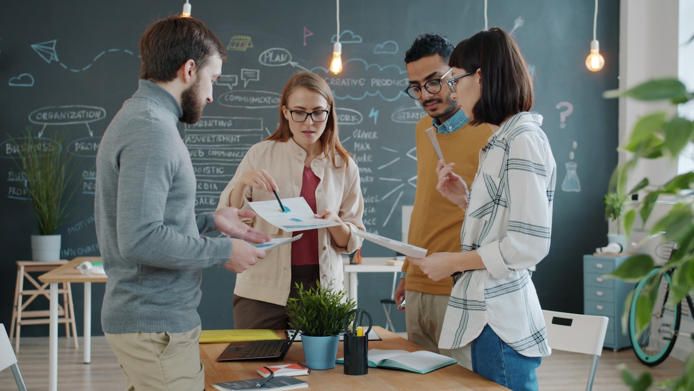 Equipe analisando ideias e gráficos durante uma conversa colaborativa